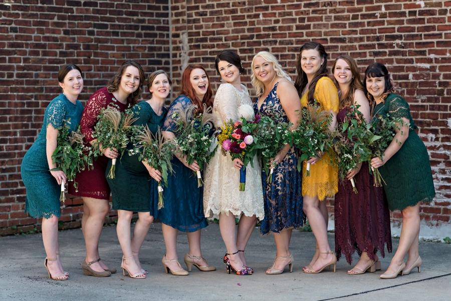 A bride and her bridesmaids in short colorful dresses.
